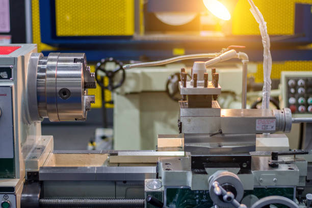 Industrial lathe machine in a workshop, ready for precision metalworking operations with a light illuminating the work area.