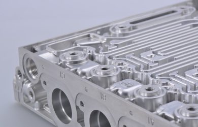 A close-up view of a meticulously machined metal component with various chambers and pathways, indicative of a sophisticated engine part.