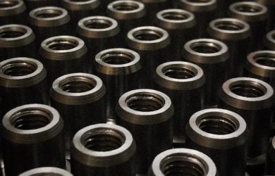 Rows of identical cylindrical metal parts with central threaded holes.